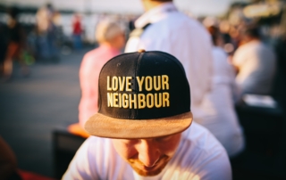 man wearing black cap with love your neighbour print during daytime