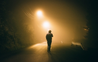 man standing in concrete road during night time