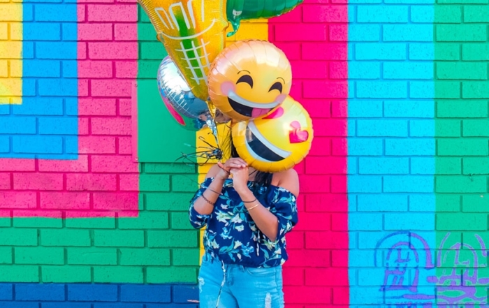 woman covering face with assorted ballons