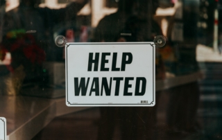 a sign that says help wanted on a glass door