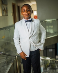 A young boy in a white suit and bowtie